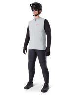 Alpinestars A-Dura Thermal Vest, szara tytanowa kamizelka rowerowa z różowym logo, noszona przez modela w czarnej koszulce z długim rękawem, ciemnoszarych spodniach i czarnym kasku MTB, profesjonalna odzież do jazdy w niskich temperaturach