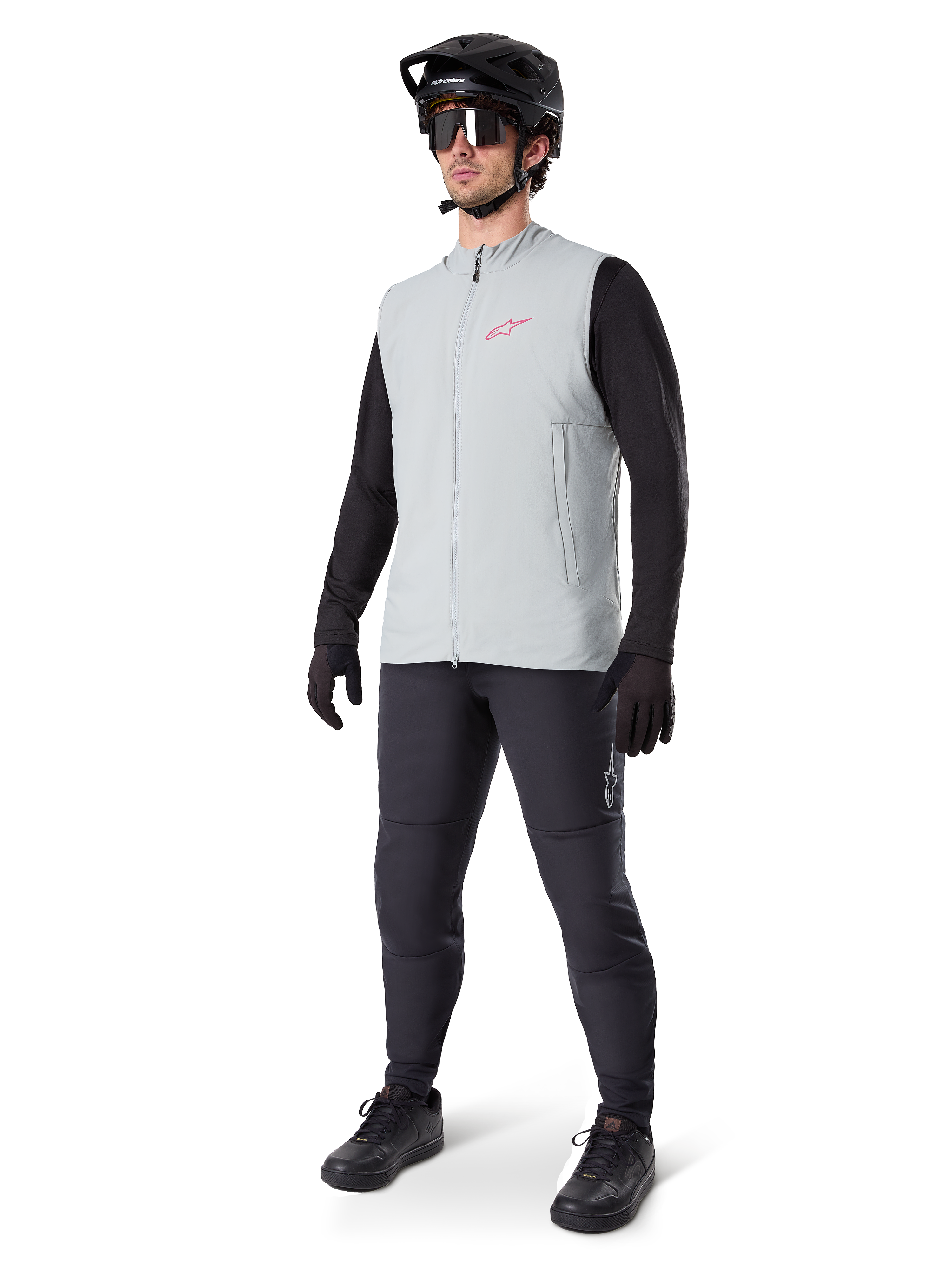 Alpinestars A-Dura Thermal Vest, szara tytanowa kamizelka rowerowa z różowym logo, noszona przez modela w czarnej koszulce z długim rękawem, ciemnoszarych spodniach i czarnym kasku MTB, profesjonalna odzież do jazdy w niskich temperaturach