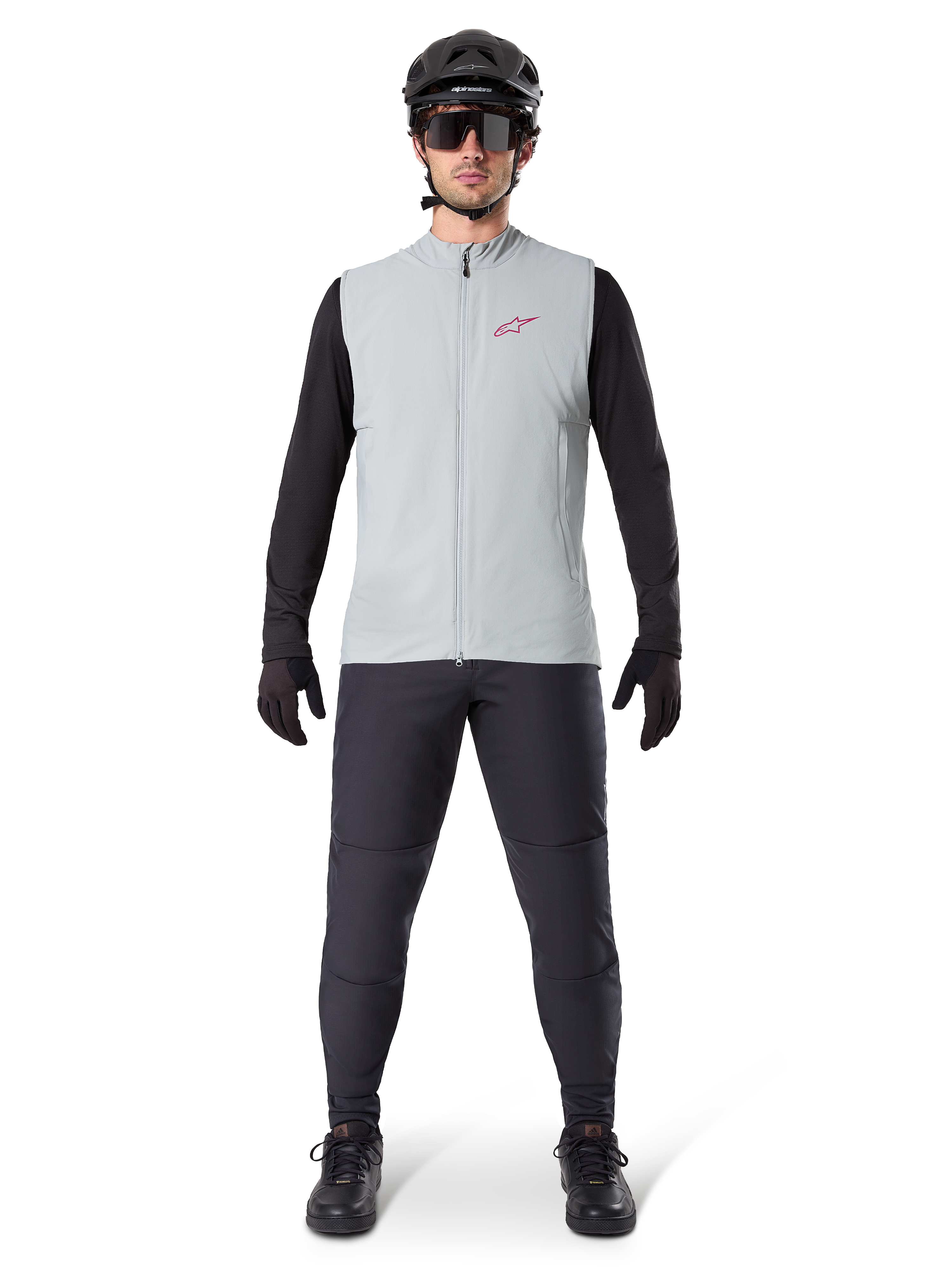 Kamizelka termiczna Alpinestars A-Dura, kamizelka rowerowa, szary Titanium, zestawiona z czarną koszulką z długim rękawem i czarnymi spodniami, czarny kask i okulary przeciwsłoneczne, czerwone logo Alpinestars, lekka izolacja termiczna do jazdy na rowerze górskim