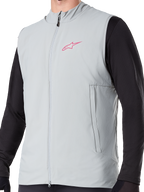 Alpinestars A-Dura Thermal Vest, ocieplana kamizelka rowerowa w kolorze Titanium Gray, różowe logo gwiazdy na piersi, założona na czarną bluzkę z długim rękawem, posiada pionową kieszeń na zamek i pełny zamek z przodu, zaprojektowana do jazdy MTB w chłodne dni.