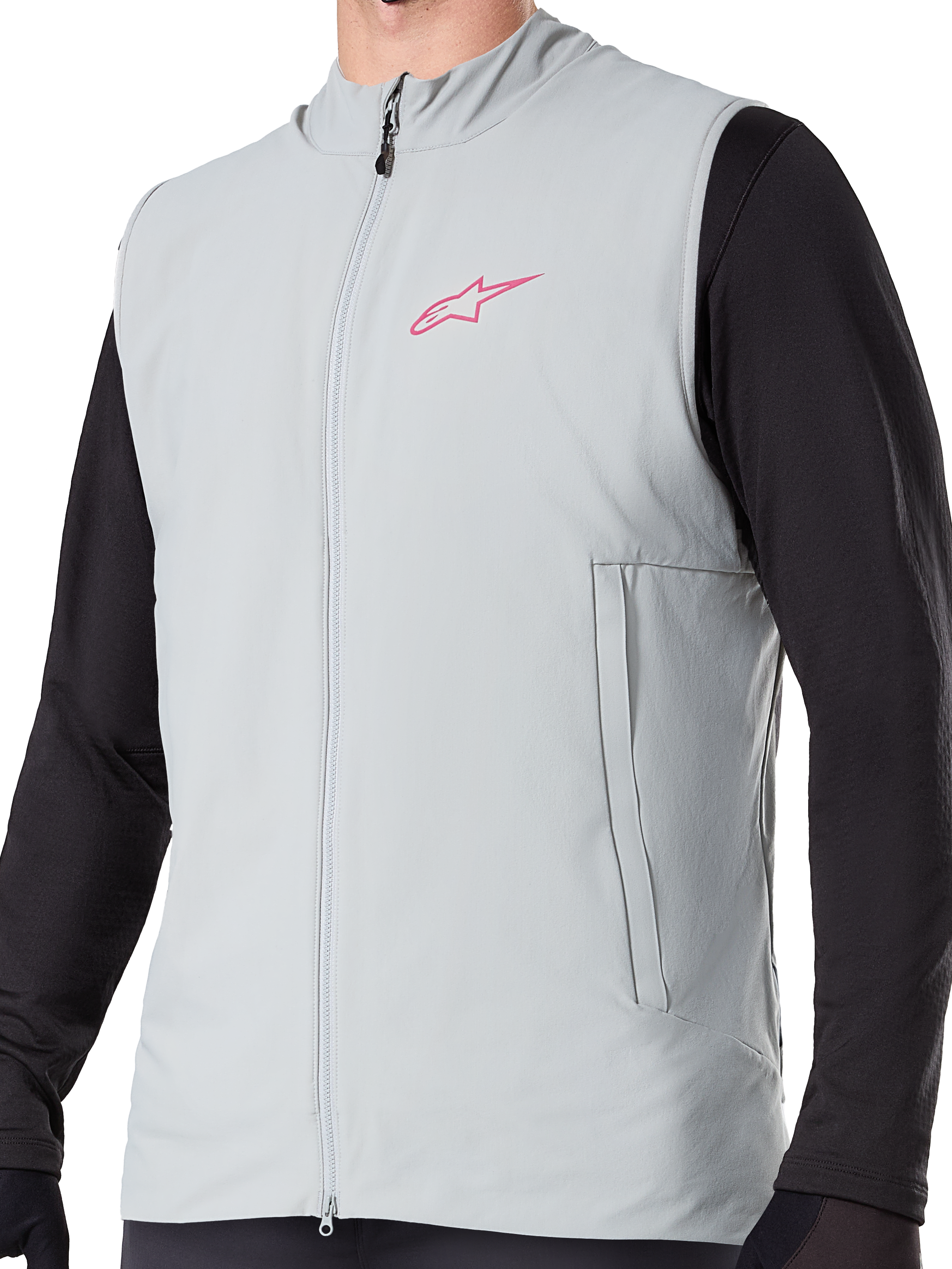 Alpinestars A-Dura Thermal Vest, ocieplana kamizelka rowerowa w kolorze Titanium Gray, różowe logo gwiazdy na piersi, założona na czarną bluzkę z długim rękawem, posiada pionową kieszeń na zamek i pełny zamek z przodu, zaprojektowana do jazdy MTB w chłodne dni.
