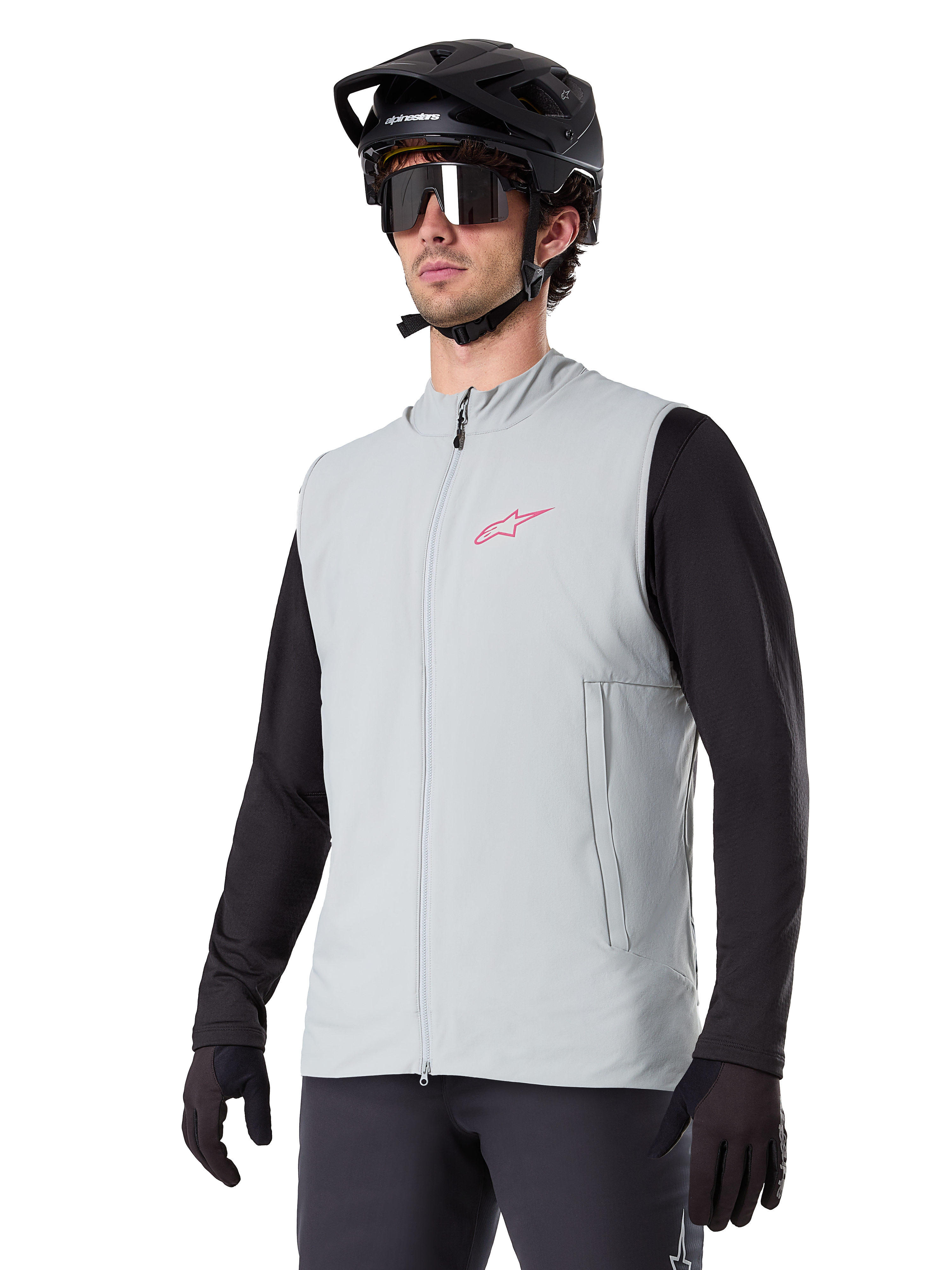 Kamizelka termiczna Alpinestars A-Dura, Titanium Gray, rowerowa kamizelka ocieplana, założona na czarną koszulkę z długim rękawem, z czarnym kaskiem MTB i rękawiczkami, różowe logo na piersi, pionowe boczne kieszenie na zamek