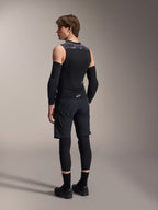 Męski model widoczny od tyłu w kamizelce ochronnej Alpinestars A-Motion Plasma Protection Vest, Black Camo, siateczkowy bezrękawnik z zintegrowanym ochraniaczem pleców, szary wzór kamuflażu na ramionach, czarne ochraniacze łokci i spodenki MTB, profesjonalna odzież rowerowa