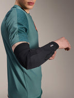 Alpinestars A-Motion Plasma Elbow Sleeve, rowerowy ochraniacz łokcia, czarny, noszony przez rowerzystę w morskiej koszulce, z logo Alpinestars i brandingiem Nucleon Plasma, smukła i oddychająca konstrukcja dla ochrony MTB