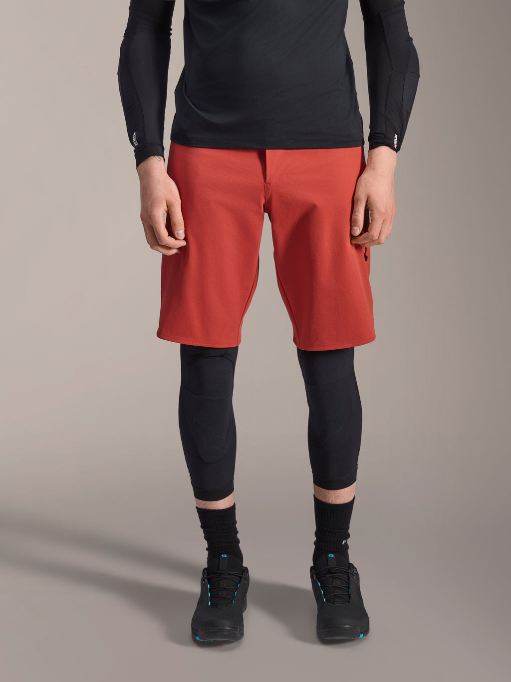 Alpinestars A-Motion Plasma Knee Sleeve, czarne ochraniacze na kolana MTB, noszone z czerwonymi spodenkami i czarną bluzą z długim rękawem, smukły profil, ergonomiczny design, lekka konstrukcja z siateczki do jazdy w terenie
