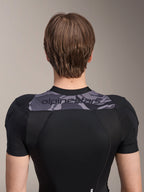 Alpinestars A-Motion Plasma Protection Jacket - Short Sleeve, widok z tyłu na górną część tułowia, czarna z szarym panelem moro na ramionach z logo Alpinestars, oddychająca konstrukcja z elastycznej siatki dla ochrony MTB