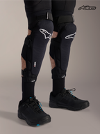 Alpinestars Ochraniacz Kolano / Piszczel A-Impact Plasma Pro, czarne ochraniacze na kolana i golenie MTB z białym logo, na modelu prezentującym potrójne zapięcie na paski i ochronę Nucleon Plasma