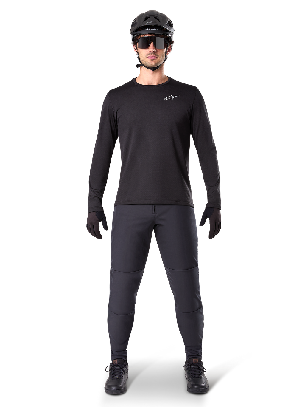 Alpinestars A-Dura Thermal Pant, czarne spodnie rowerowe MTB, noszone przez rowerzystę w kompletnym stroju z czarną koszulką z długim rękawem, kaskiem i okularami, wytrzymałe spodnie o regularnym kroju do jazdy w chłodne dni