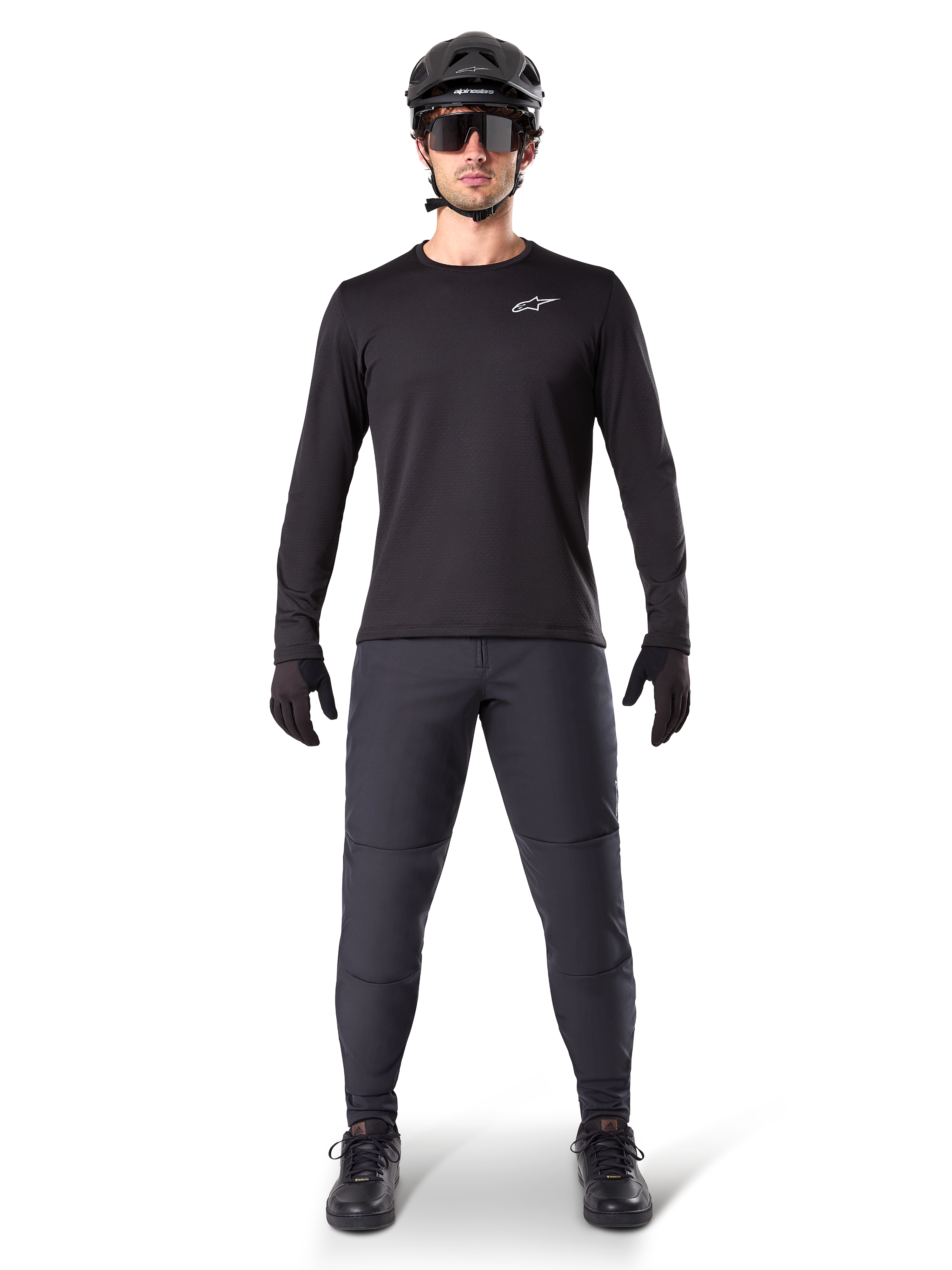 Alpinestars A-Dura Thermal Pant, czarne spodnie rowerowe MTB, noszone przez rowerzystę w kompletnym stroju z czarną koszulką z długim rękawem, kaskiem i okularami, wytrzymałe spodnie o regularnym kroju do jazdy w chłodne dni