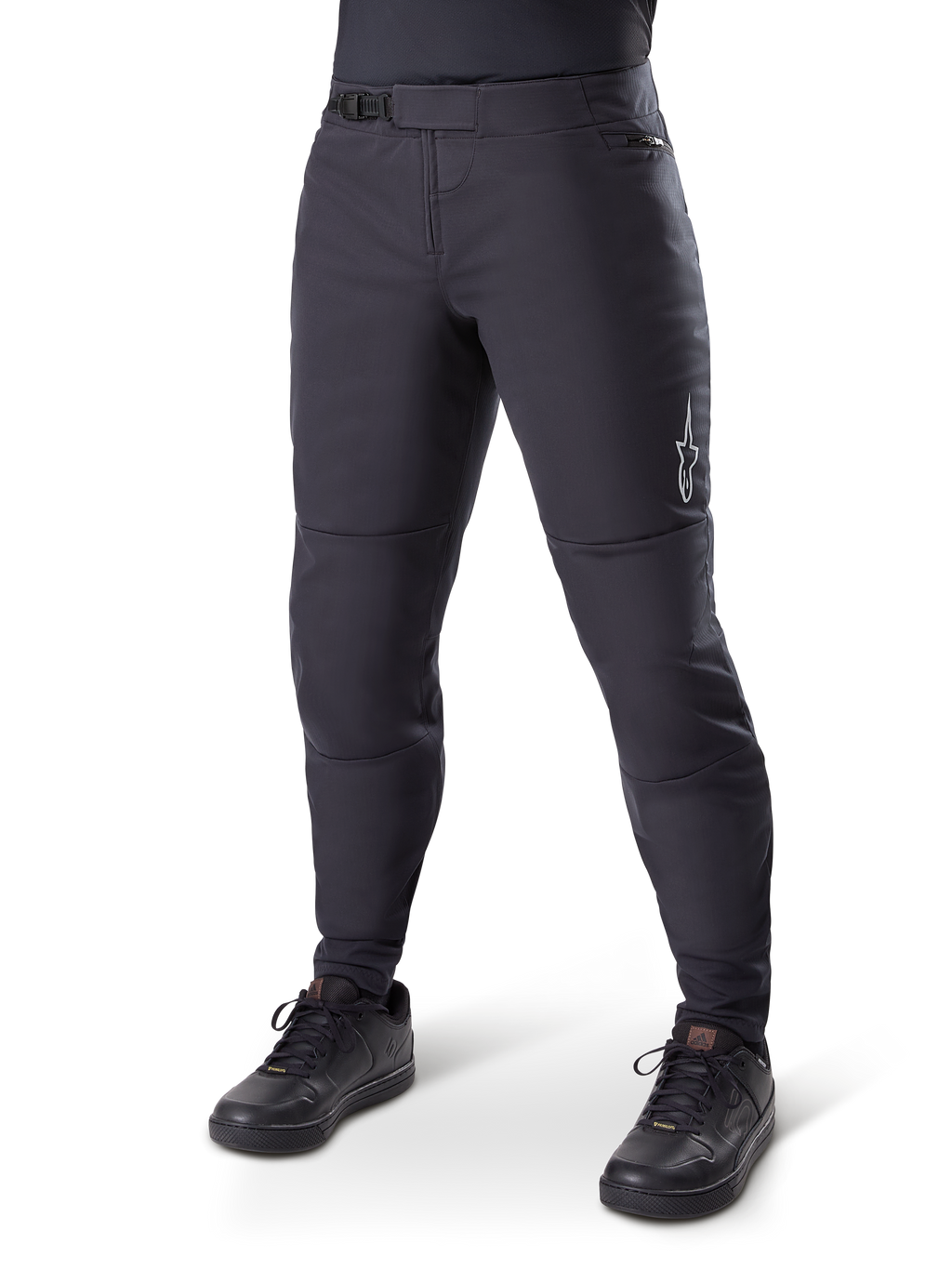 Alpinestars A-Dura Thermal Pant, czarne spodnie rowerowe MTB, noszone z czarnymi butami rowerowymi, z zapięciem na zapadkę w pasie, małym białym logo na udzie, zwężany krój do jazdy w chłodne dni