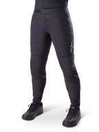 Alpinestars A-Dura Thermal Pant, czarne spodnie rowerowe MTB, noszone z czarnymi butami rowerowymi, z zapięciem na zapadkę w pasie, małym białym logo na udzie, zwężany krój do jazdy w chłodne dni