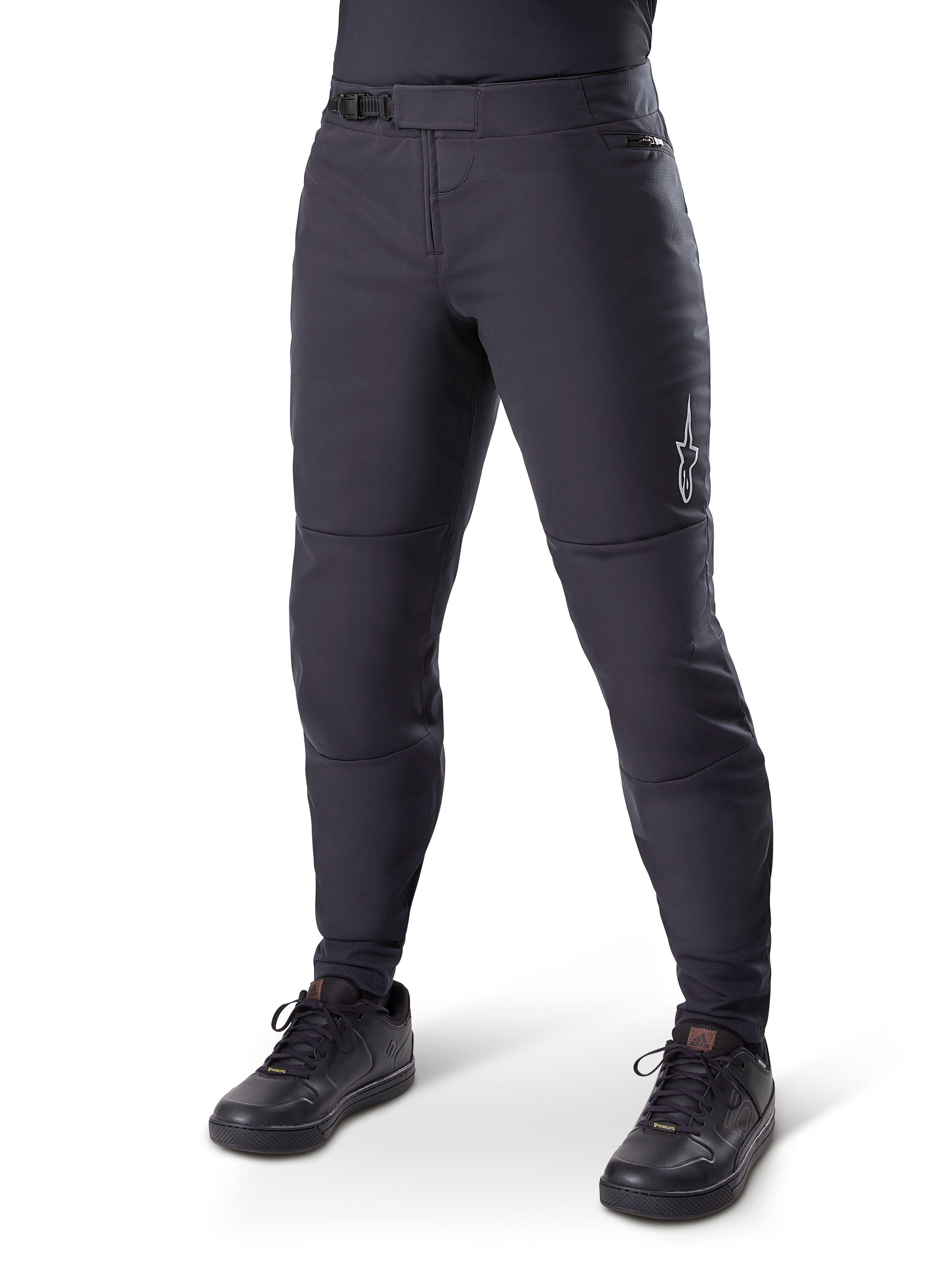 Alpinestars A-Dura Thermal Pant, czarne spodnie rowerowe MTB, noszone z czarnymi butami rowerowymi, z zapięciem na zapadkę w pasie, małym białym logo na udzie, zwężany krój do jazdy w chłodne dni