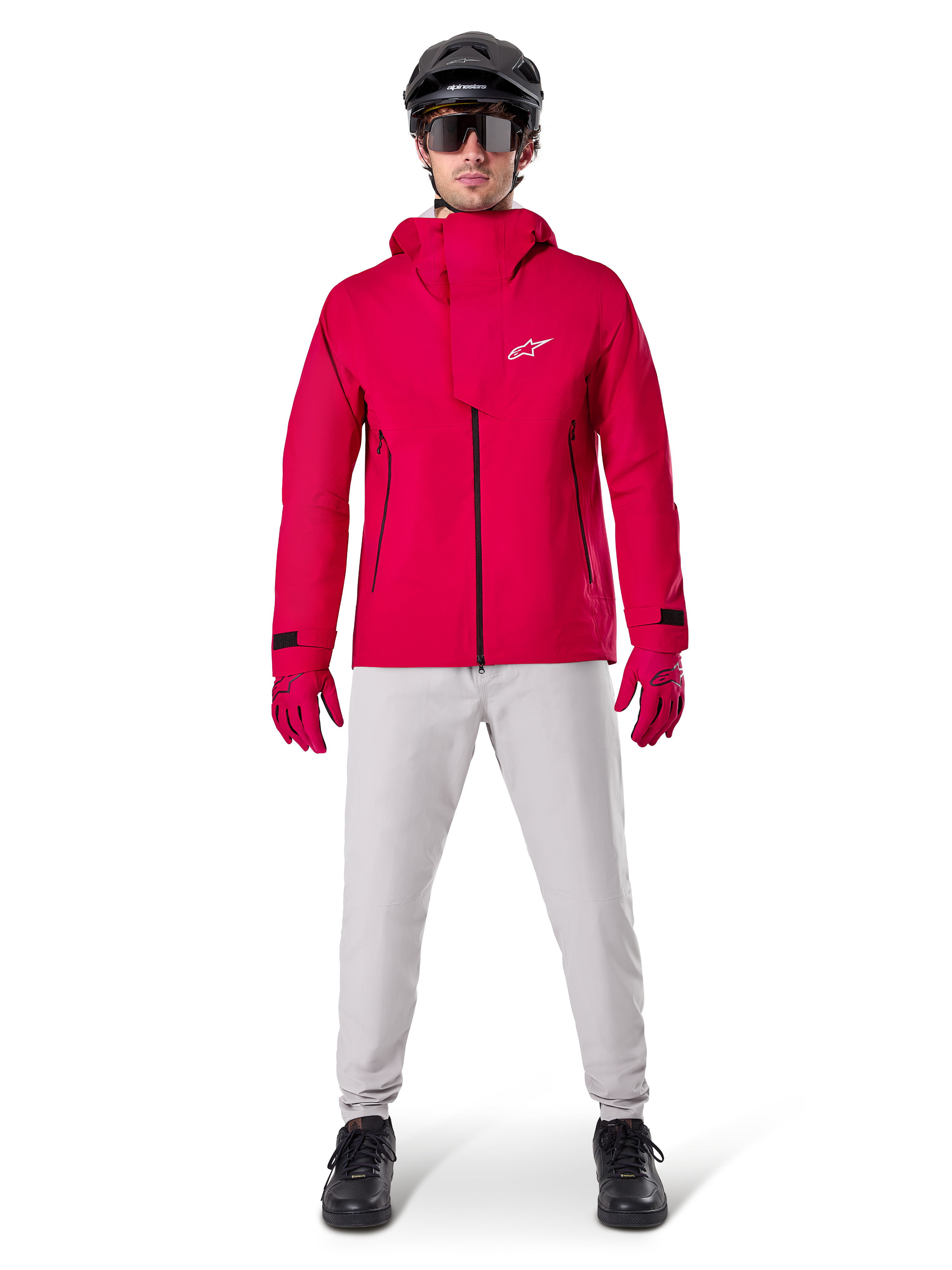 Spodnie Alpinestars A-Dura Waterproof, spodnie MTB, kolor Titanium Gray, noszone z jasnoczerwoną kurtką z kapturem, czerwonymi rękawicami i czarnym kaskiem rowerowym MTB, profesjonalna wodoodporna odzież rowerowa na mokre warunki na szlaku