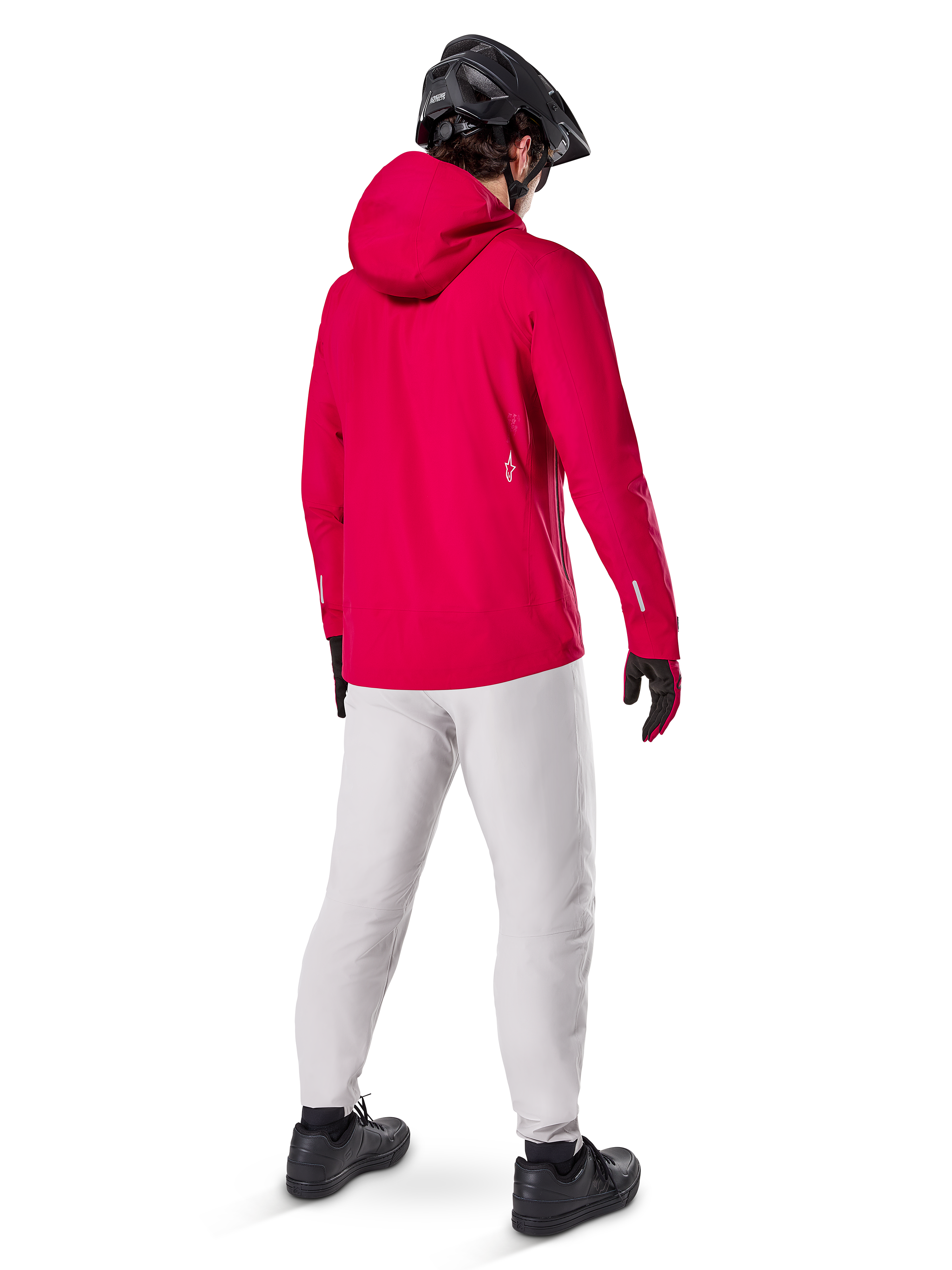 Alpinestars A-Dura Waterproof Pants w kolorze Titanium, widok z tyłu na rowerzystę w jasnoszarych technicznych spodniach MTB, jaskrawoczerwona kurtka z kapturem i czarny kask, wytrzymała wodoodporna odzież na rower w mokrych warunkach