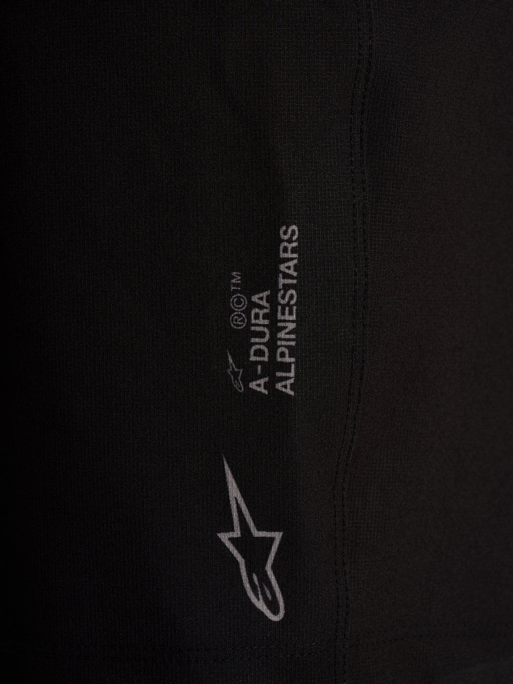 Szczegół czarnych szortów Alpinestars A-Dura Ride Liner z białym logo na elastycznej tkaninie 4-way stretch.
