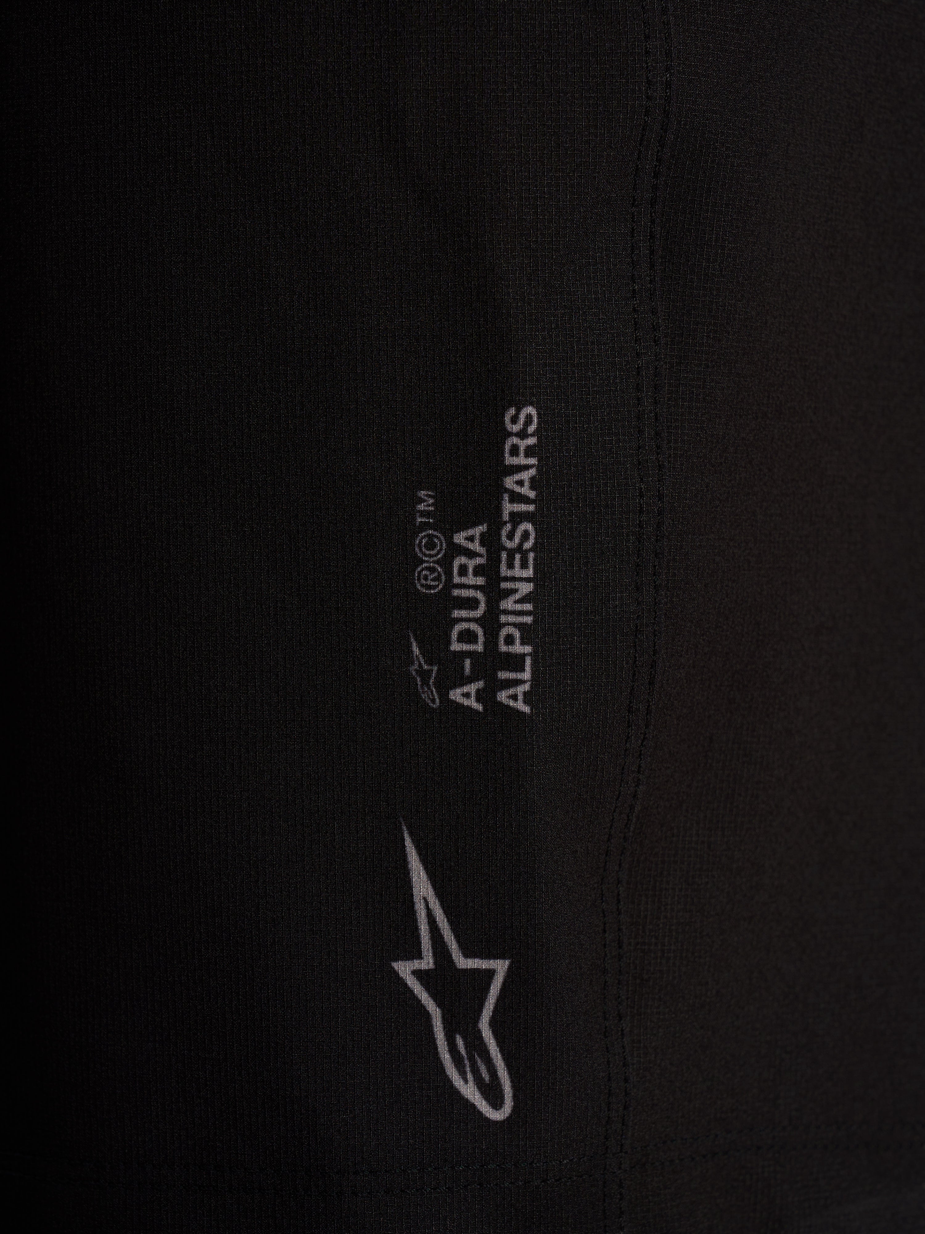 Szczegół czarnych szortów Alpinestars A-Dura Ride Liner z białym logo na elastycznej tkaninie 4-way stretch.
