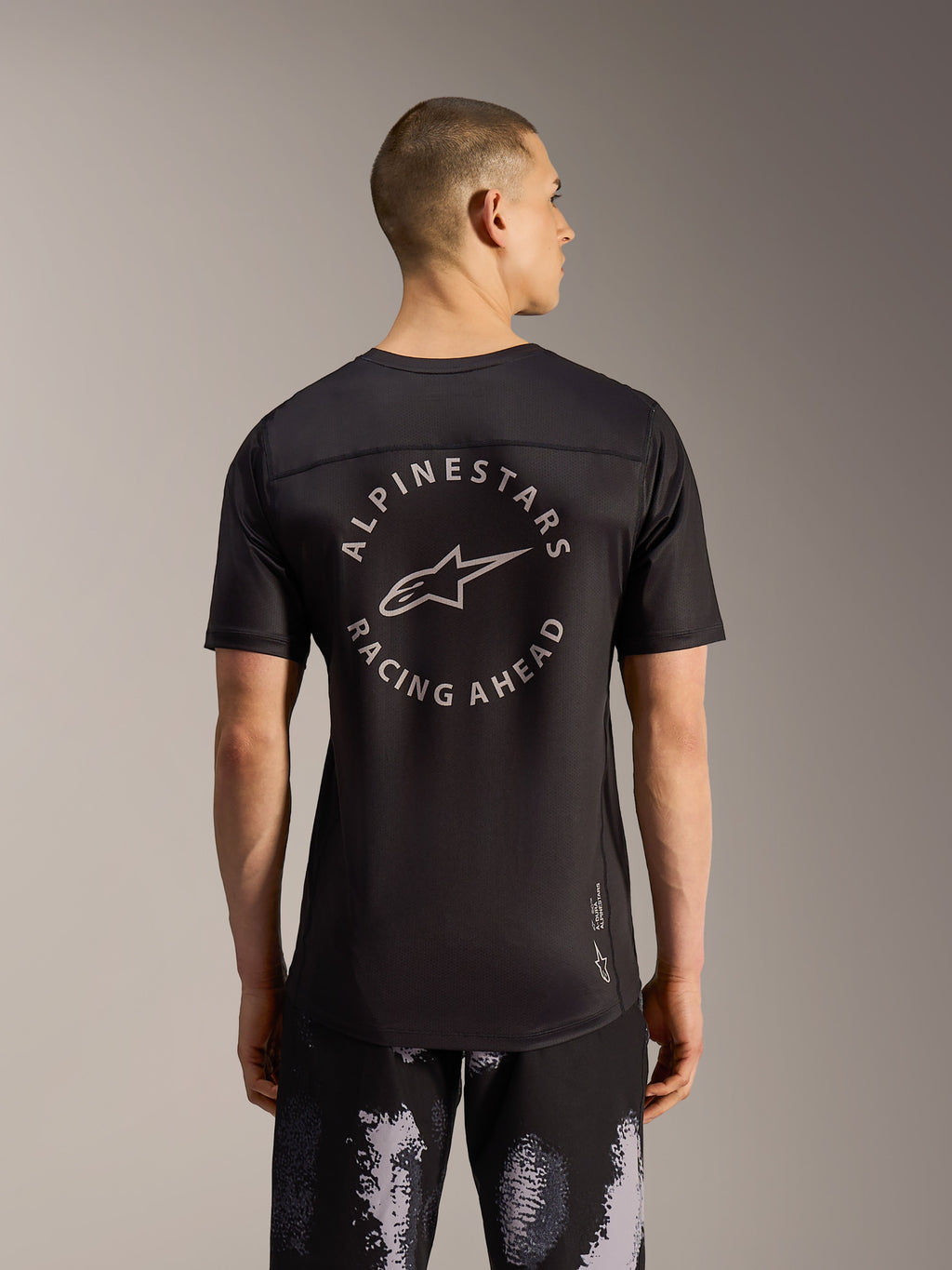 Szorty Alpinestars A-Dura Ride Black Camo i czarna koszulka MTB z okrągłym logo na plecach, widok od tyłu na modelu.