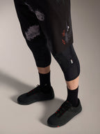 Szorty Alpinestars A-Dura Ride Black Camo z pomarańczowym logo, noszone z ochraniaczami kolan i butami MTB.