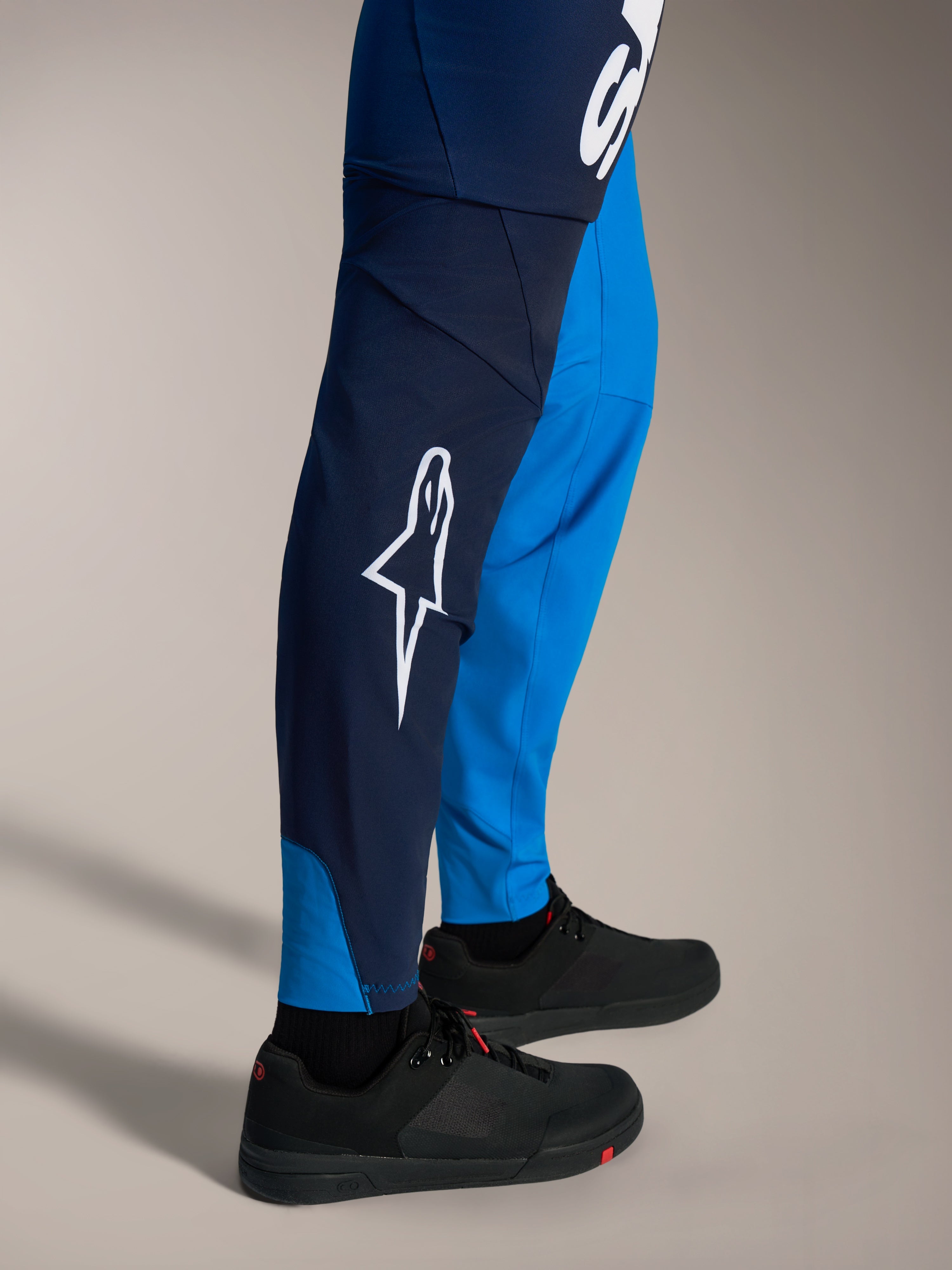 Spodnie MTB Alpinestars A-Supra Elite, cieniowany niebieski, białe logo Astars, dopasowany krój wyścigowy.