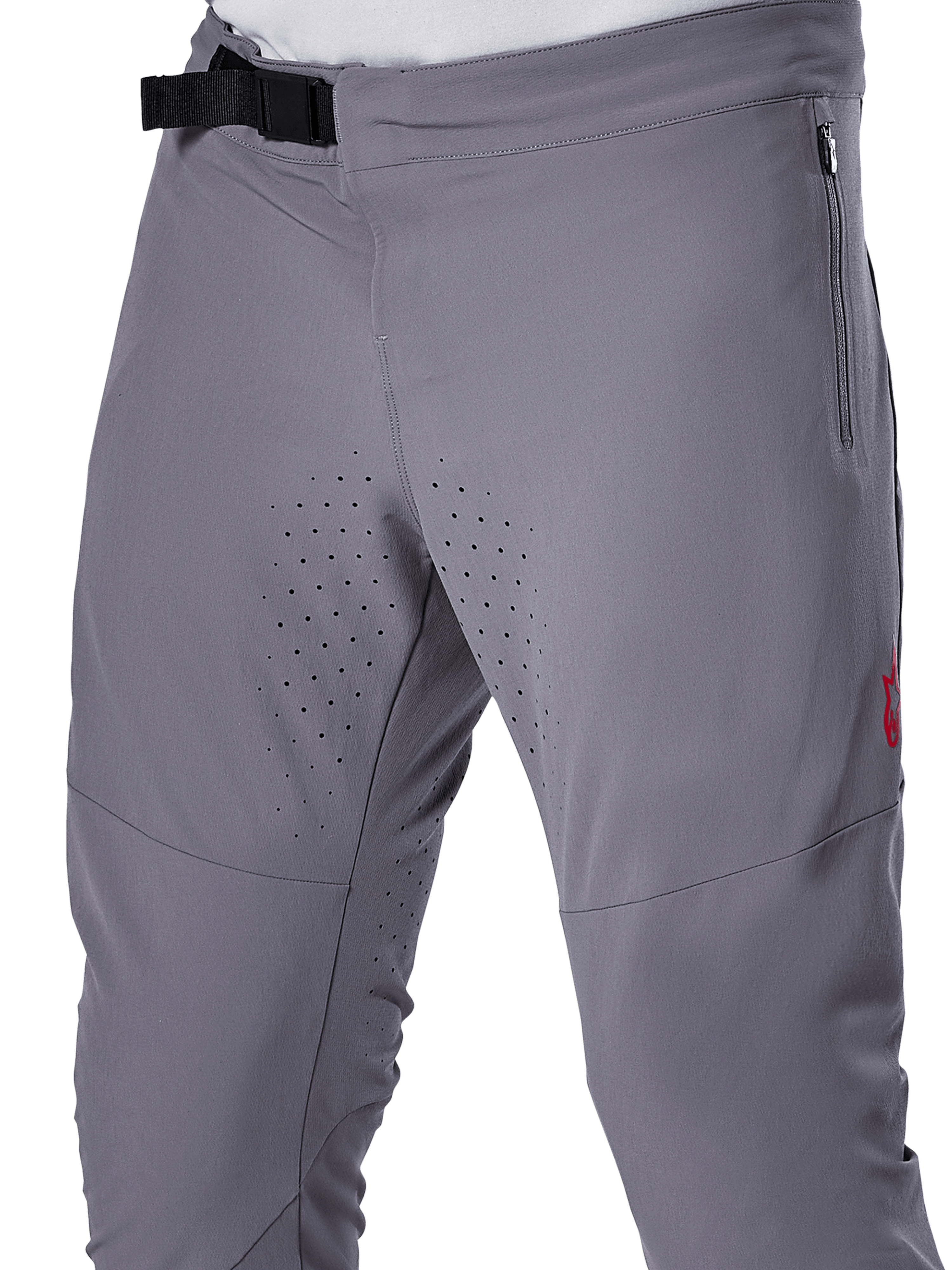 Alpinestars A-Aria Elite Pants, spodnie rowerowe MTB, ciemnoszare, zbliżenie przedstawiające magnetyczne zapięcie na klamrę, boczną kieszeń na zamek oraz laserowo wycinane perforacje wentylacyjne na wewnętrznej stronie ud, zaprojektowane z myślą o wydajności na szlaku.