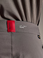 Alpinestars A-Dura Elite Pants, spodnie MTB, ciemnoszare, zbliżenie na pas z czerwoną metką ASTARS i białym logo DURA, teksturowana tkanina Cordura i detale brandingowe premium