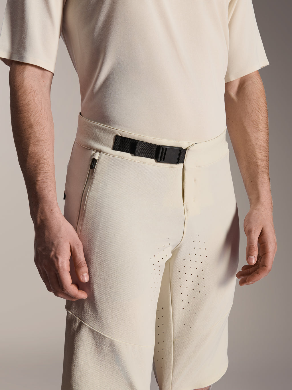 Alpinestars A-Aria Elite Shorts, spodenki rowerowe MTB, ecru, zbliżenie na czarną magnetyczną klamrę, boczną kieszeń na zamek i laserowo wycinaną wentylację, techniczna odzież rowerowa