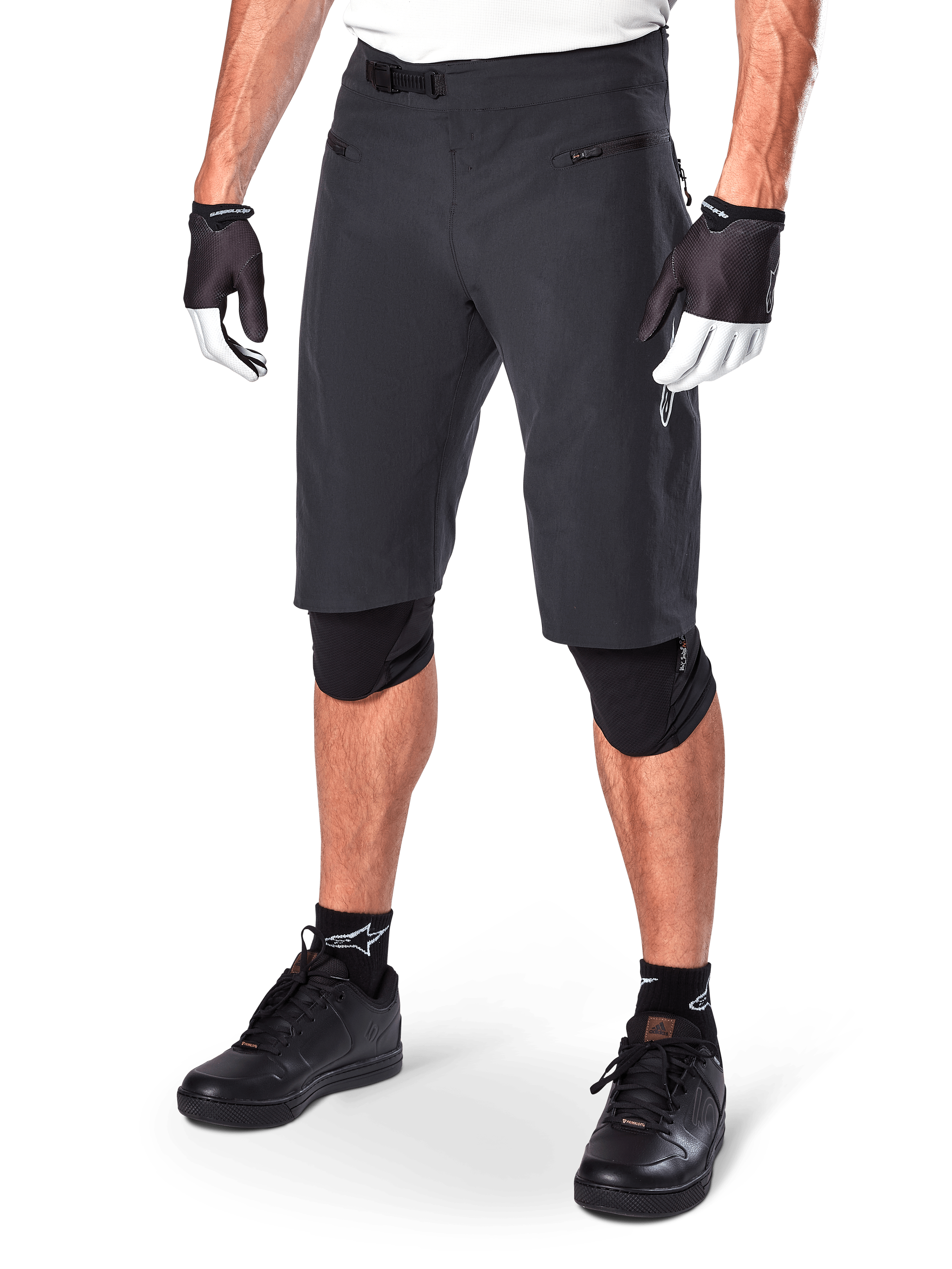 Alpinestars A-Aria Shorts, spodenki do kolarstwa górskiego, czarne, o długości do kolan, z przednimi kieszeniami na zamek i regulowaną klamrą zapadkową w pasie, noszone z czarnymi ochraniaczami na kolana, skarpetami i rękawiczkami rowerowymi