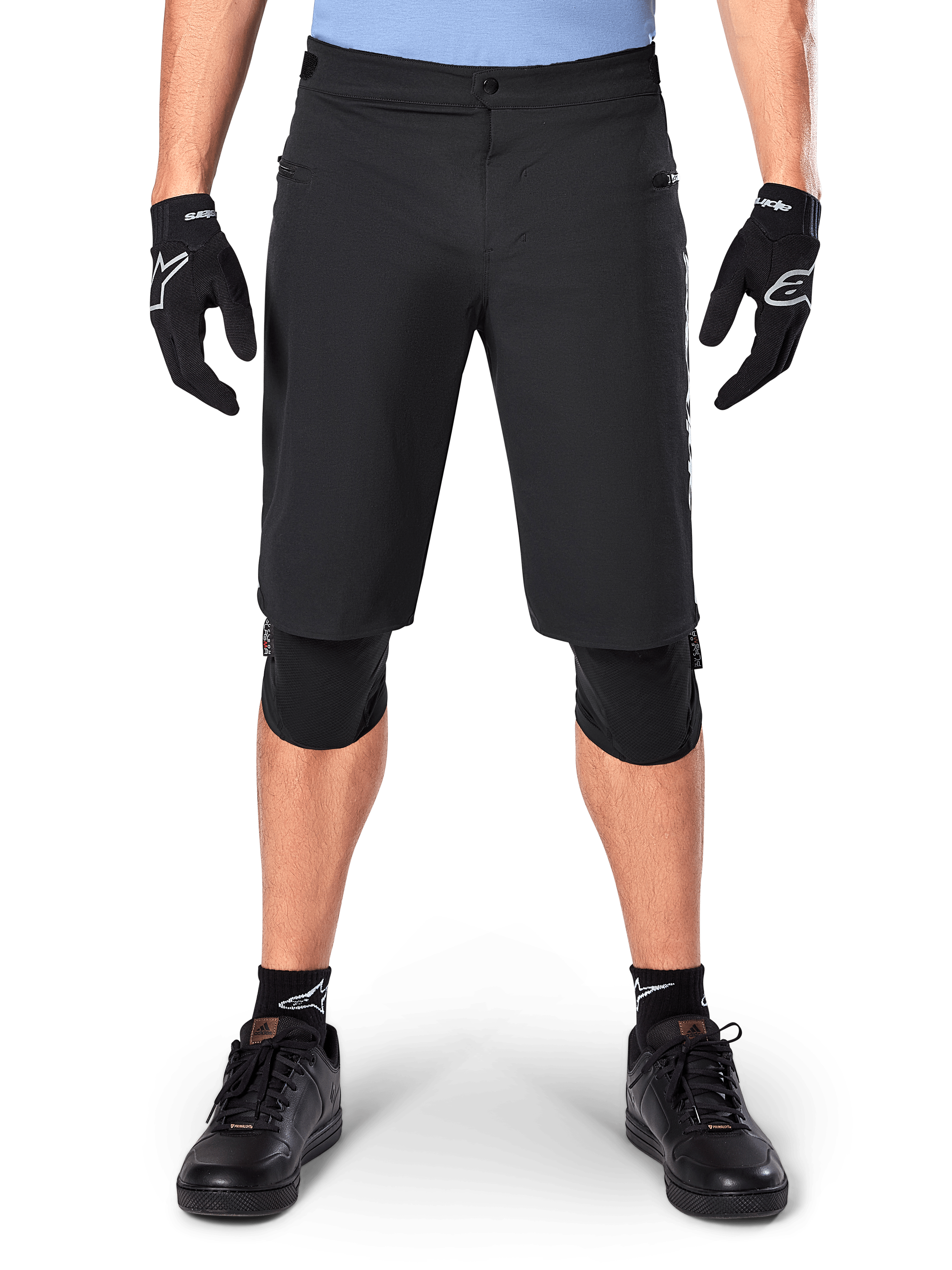 Alpinestars A-Dura Elite Shorts, czarne spodenki rowerowe MTB, noszone przez rowerzystę w czarnych rękawiczkach i ochraniaczach kolan, zapięcie na zatrzask, kieszenie na zamek, wytrzymały materiał Cordura do jazdy w terenie