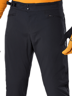 Alpinestars A-Dura Pants, czarne spodnie rowerowe MTB, zbliżenie na podwójne zapięcie na zatrzaski w pasie, boczną regulację dopasowania i kieszenie zapinane na zamek, zestawione z pomarańczową koszulką i rękawicami