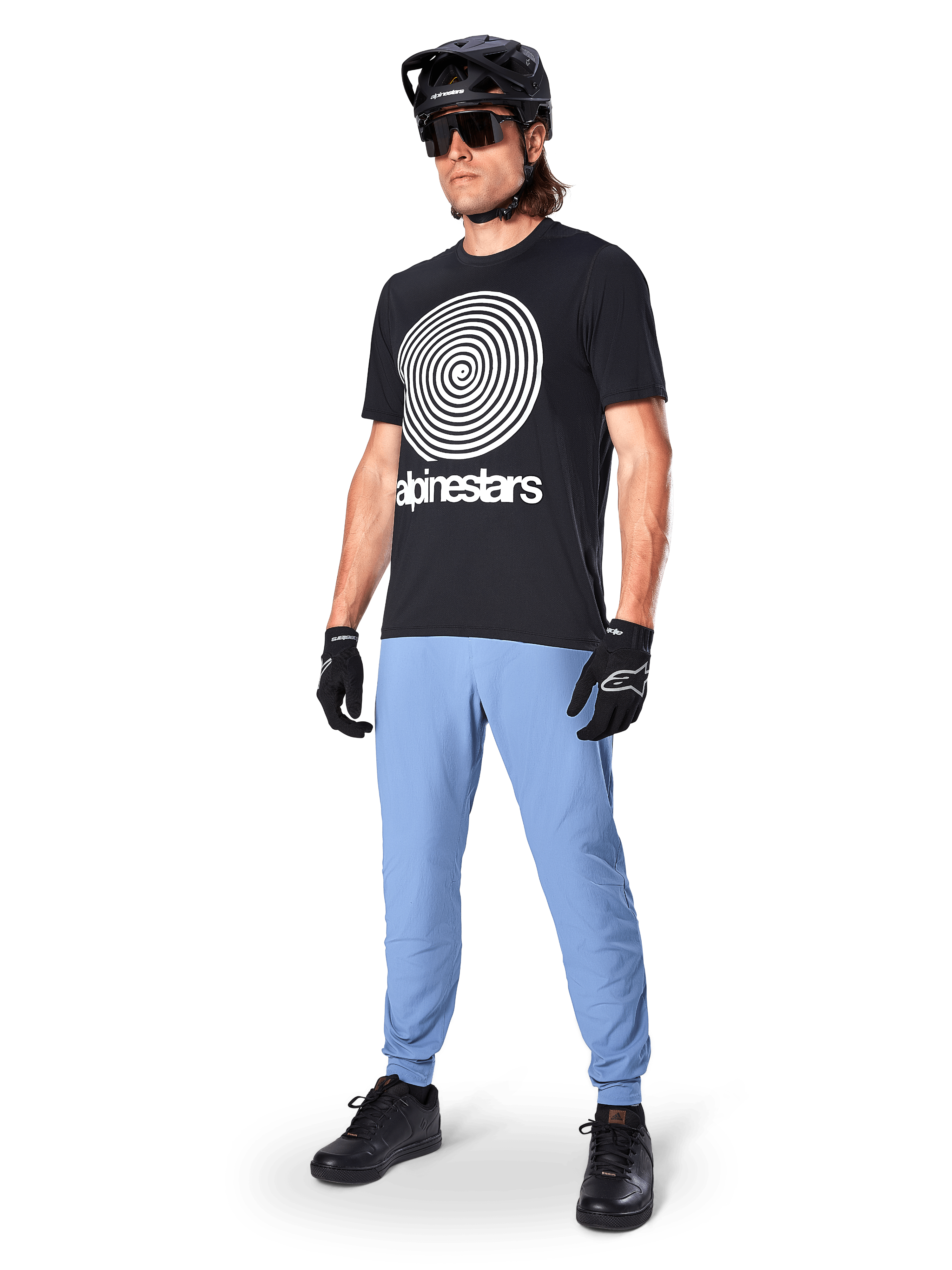 Spodnie Alpinestars A-Dura, spodnie MTB, Infinity Blue, noszone z czarnym t-shirtem z białym spiralnym logo, czarnym kaskiem, okularami przeciwsłonecznymi i czarnymi rękawiczkami, profesjonalny sprzęt do kolarstwa górskiego