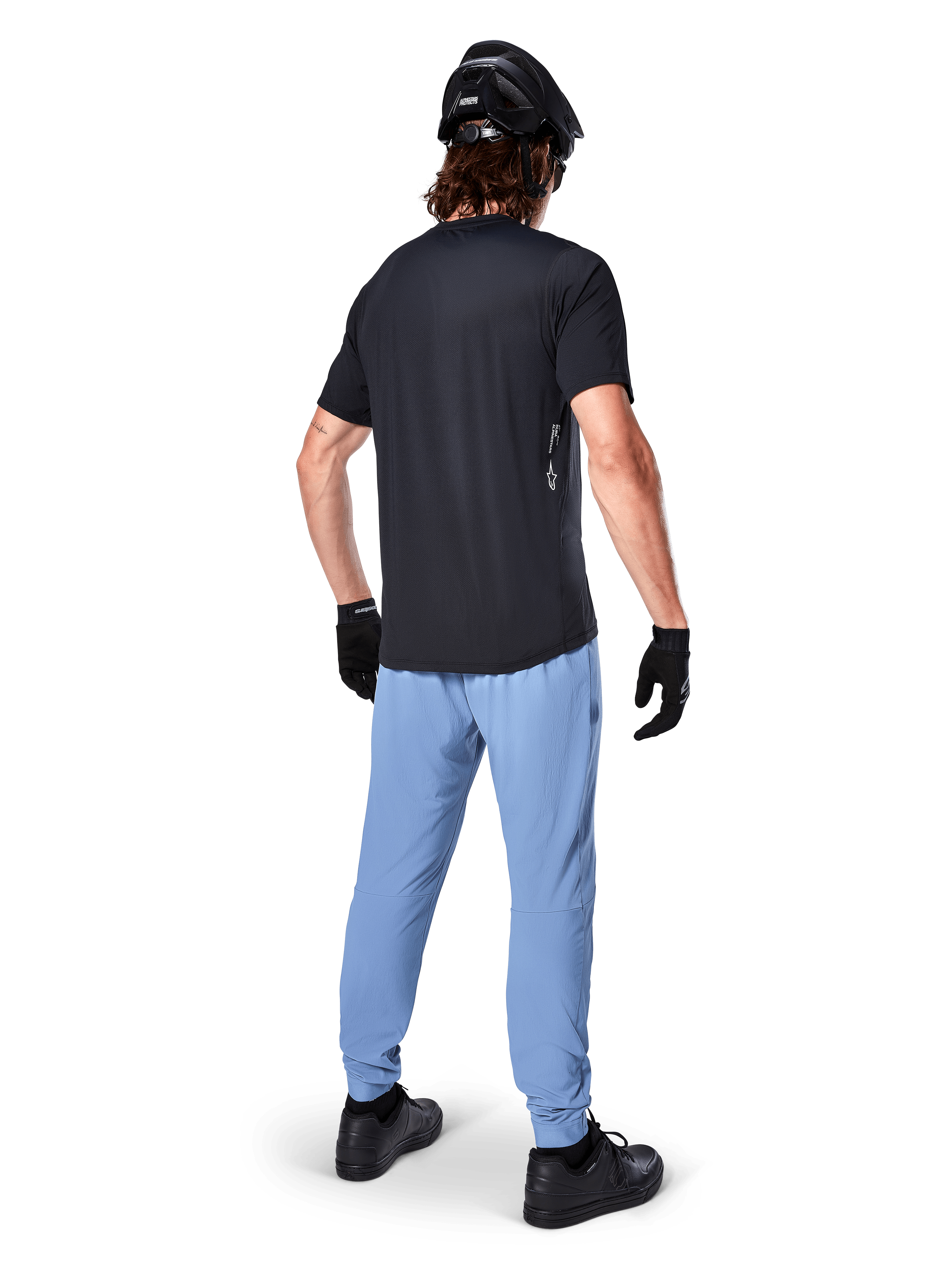 Spodnie Alpinestars A-Dura, spodnie MTB, Infinity Blue, widok z tyłu na modelu w czarnym t-shircie i czarnym kasku rowerowym, wykonane z wytrzymałej tkaniny 2-way stretch z elastycznymi mankietami, odzież wyczynowa do kolarstwa górskiego