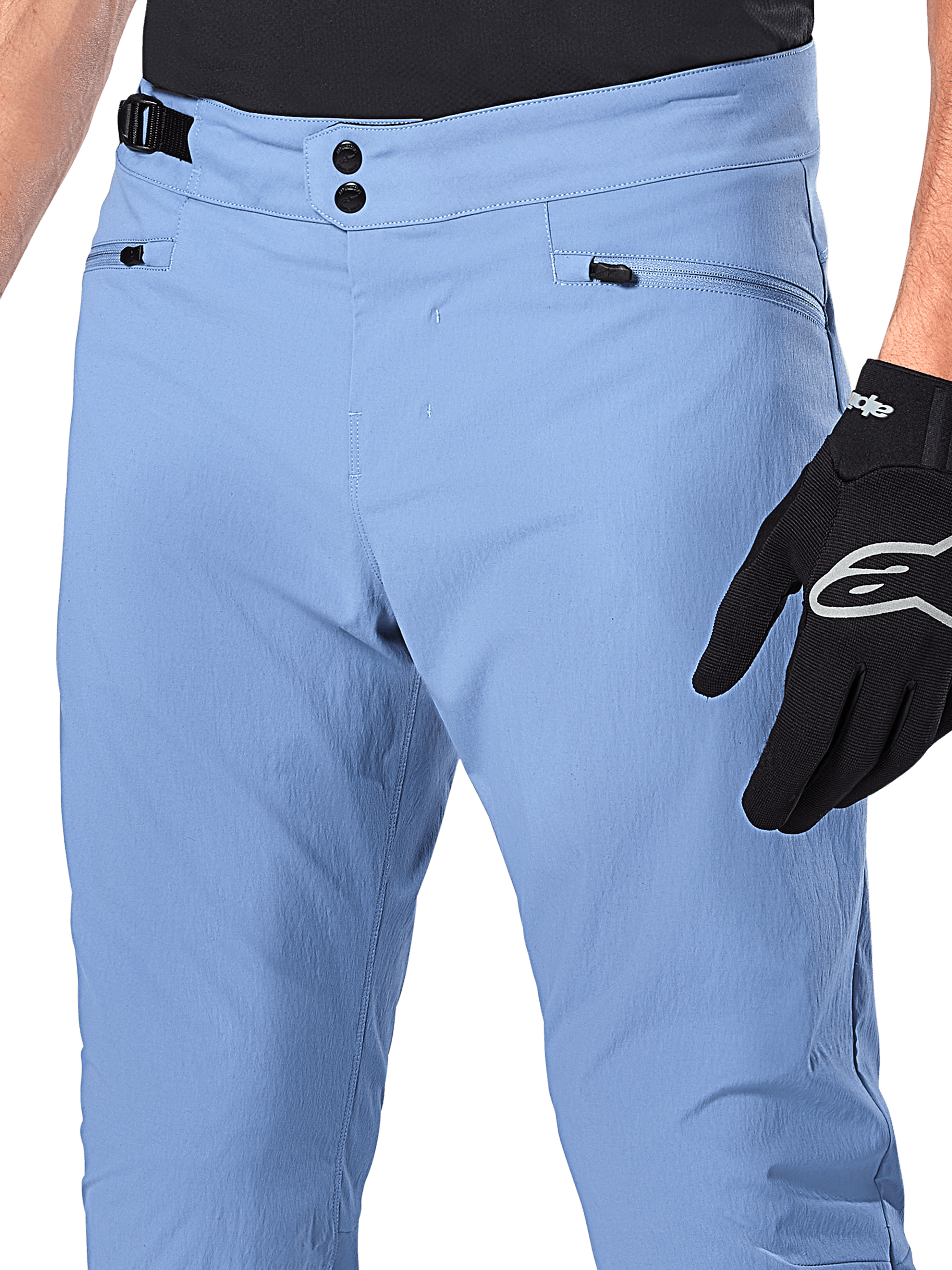 Alpinestars A-Dura Pants, spodnie rowerowe MTB, kolor Infinity Blue, zbliżenie na talię z podwójnym zapięciem na zatrzaski i bocznym regulatorem, kieszenie na zamek, noszone z czarnymi rękawicami Alpinestars