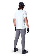 Alpinestars A-Dura Pants, ciemnoszare spodnie na rower górski widoczne z tyłu, zestawione z białym t-shirtem z krótkim rękawem, czarnym kaskiem MTB, czarnymi rękawiczkami i butami, krój regular fit z elastycznymi mankietami, wytrzymała odzież do jazdy w terenie