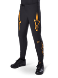 Alpinestars A-Supra Race Pants, czarne z pomarańczowymi grafikami w kształcie gwiazd, spodnie wyścigowe MTB z laserowo perforowaną wentylacją i zapięciem w pasie na zapadkę, dopasowany krój sportowy do kolarstwa terenowego