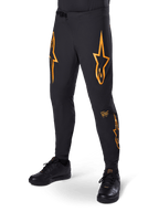 Alpinestars A-Supra Race Pants, czarne z pomarańczowymi grafikami w kształcie gwiazd, spodnie wyścigowe MTB z laserowo perforowaną wentylacją i zapięciem w pasie na zapadkę, dopasowany krój sportowy do kolarstwa terenowego