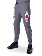 Alpinestars A-Supra Race Pants, ciemnoszare spodnie rowerowe MTB, z dużymi czerwono-białymi logotypami gwiazdy na udach, laserową perforacją dla wentylacji i zapięciem na zapadkę, sportowy krój do downhillu i enduro