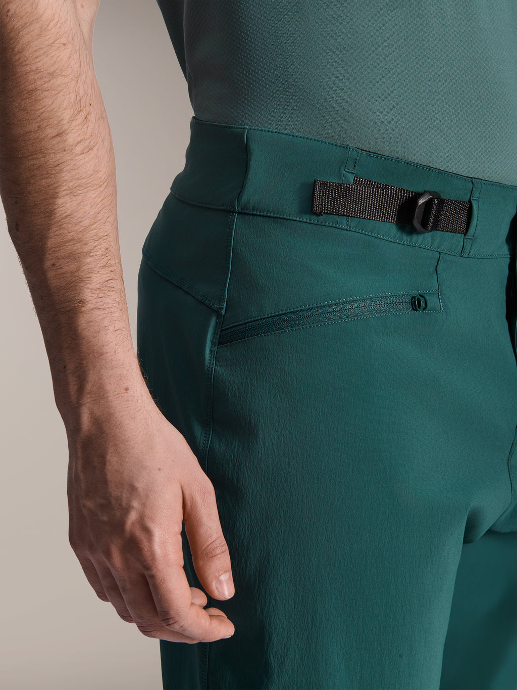 Alpinestars A-Dura Shorts, kolor Dark Pine Green, zbliżenie na regulowany boczny ściągacz w talii i kieszeń zapinaną na zamek, wytrzymała odzież do kolarstwa górskiego.