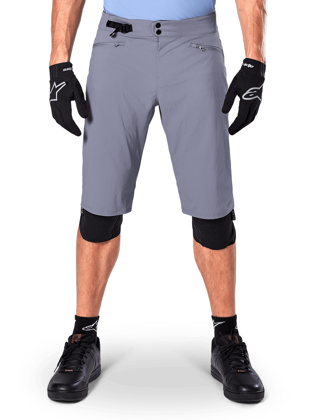 Alpinestars A-Dura Shorts, spodenki MTB, ciemnoszare, noszone z czarnymi rękawiczkami i ochraniaczami kolan Alpinestars, z podwójnym zapięciem na napy i kieszeniami na zamek z podszewką z siatki, wytrzymały materiał rozciągliwy w dwóch kierunkach do kolarstwa górskiego