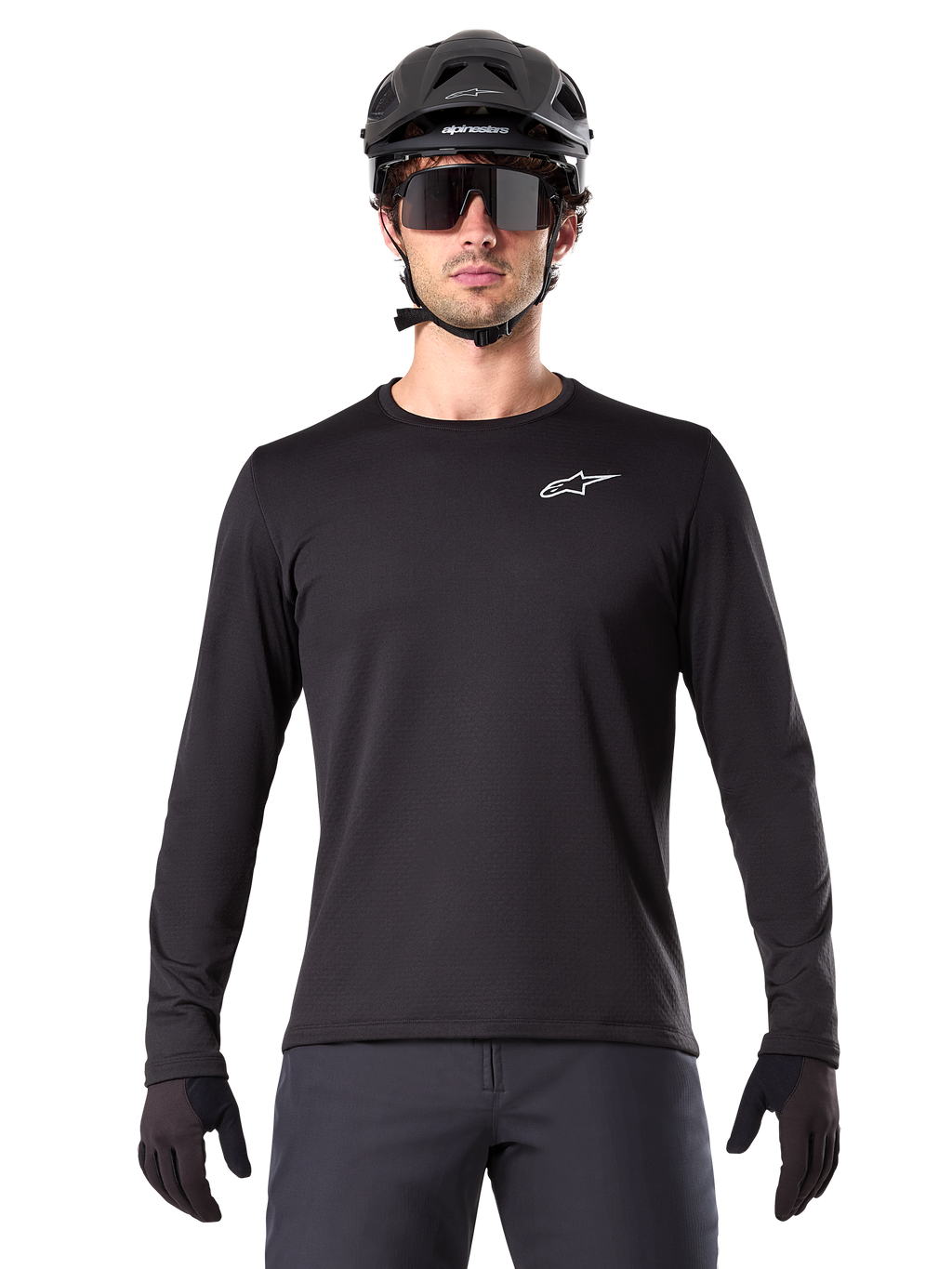 Alpinestars A-Dura Thermal Jersey, czarna koszulka rowerowa MTB z długim rękawem, noszona z czarnym kaskiem i dużymi okularami przeciwsłonecznymi, małe białe logo Alpinestars na piersi, regularny krój, odzież rowerowa MTB