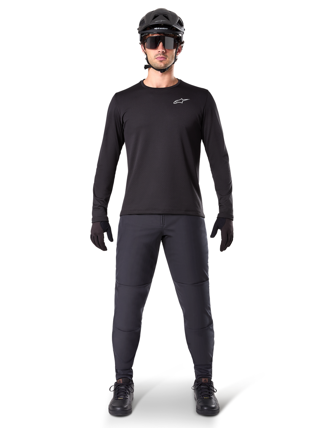 Alpinestars A-Dura Thermal Jersey, czarna koszulka rowerowa z długim rękawem, noszona z ciemnoszarymi spodniami, czarnymi rękawiczkami, czarnym kaskiem i okularami przeciwsłonecznymi, białe logo Alpinestars na piersi, dopasowany strój do jazdy na rowerze górskim w chłodne dni