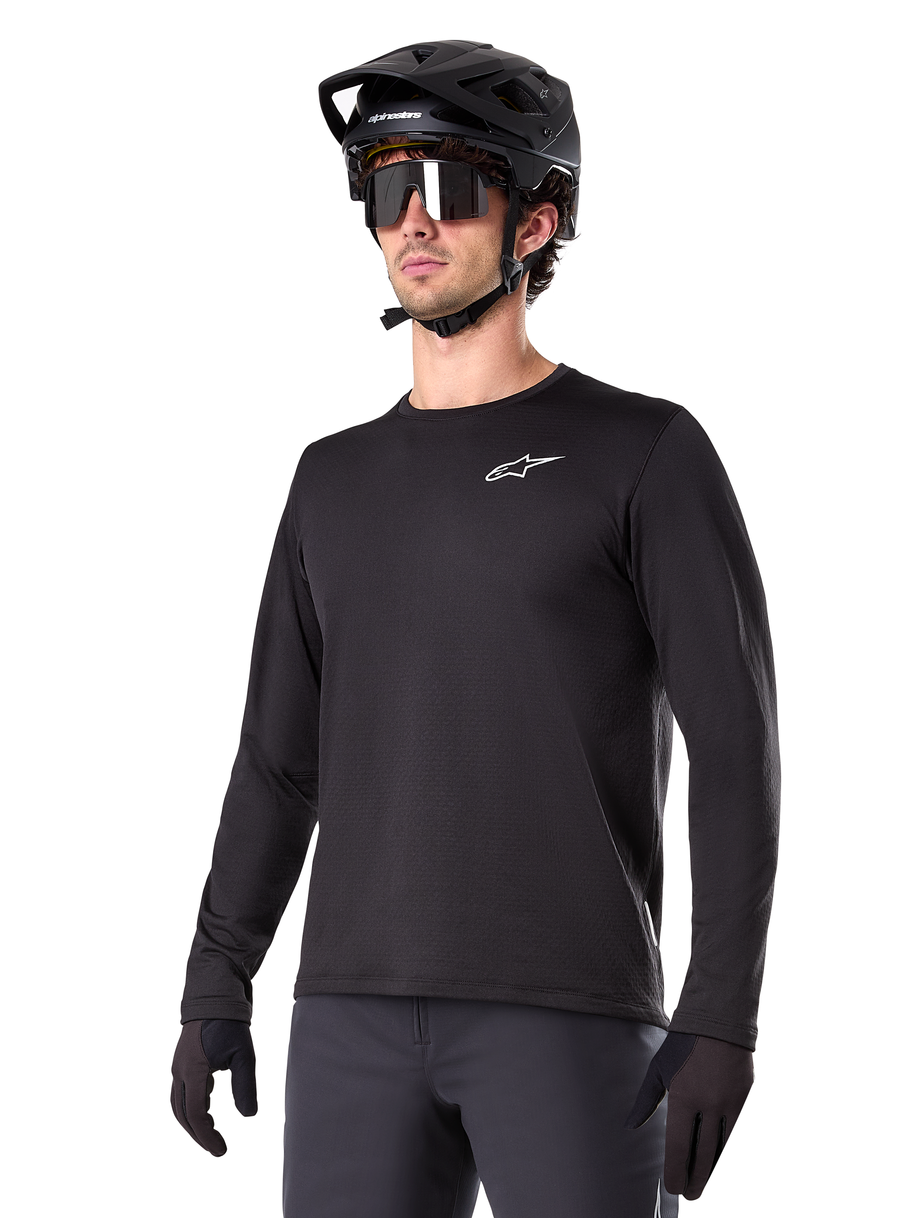 Alpinestars A-Dura Thermal Jersey, czarna koszulka MTB z długim rękawem, białe logo na piersi, noszona z czarnym kaskiem i rękawicami, nowoczesny sportowy design do jazdy na szlaku