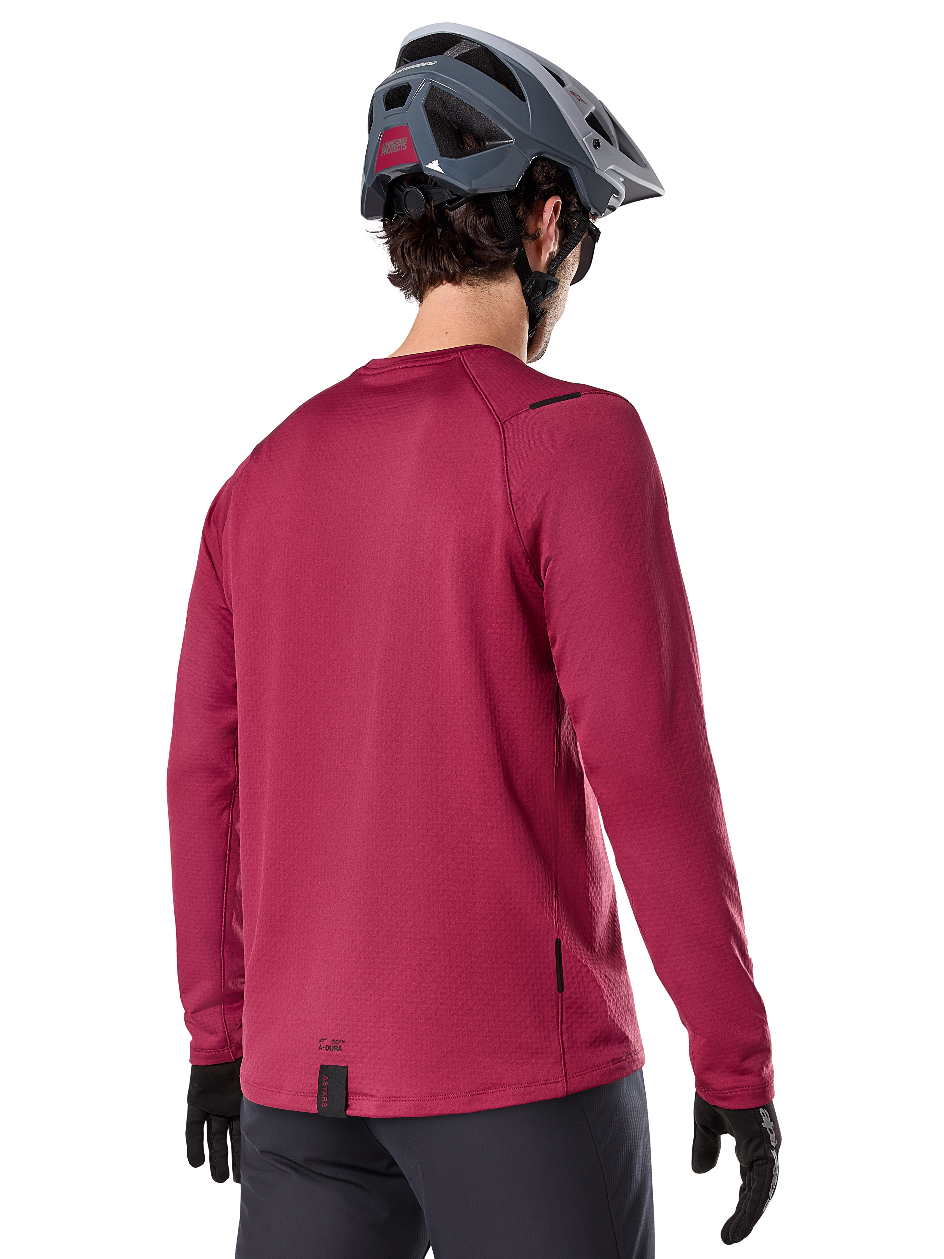 Alpinestars A-Dura Thermal Jersey, koszulka termiczna MTB z długim rękawem, bordowa, widok od tyłu na modelu w szarym kasku MTB i czarnych rękawiczkach, przedłużony tył i małe detale z logo, przeznaczona do jazdy w chłodne dni.