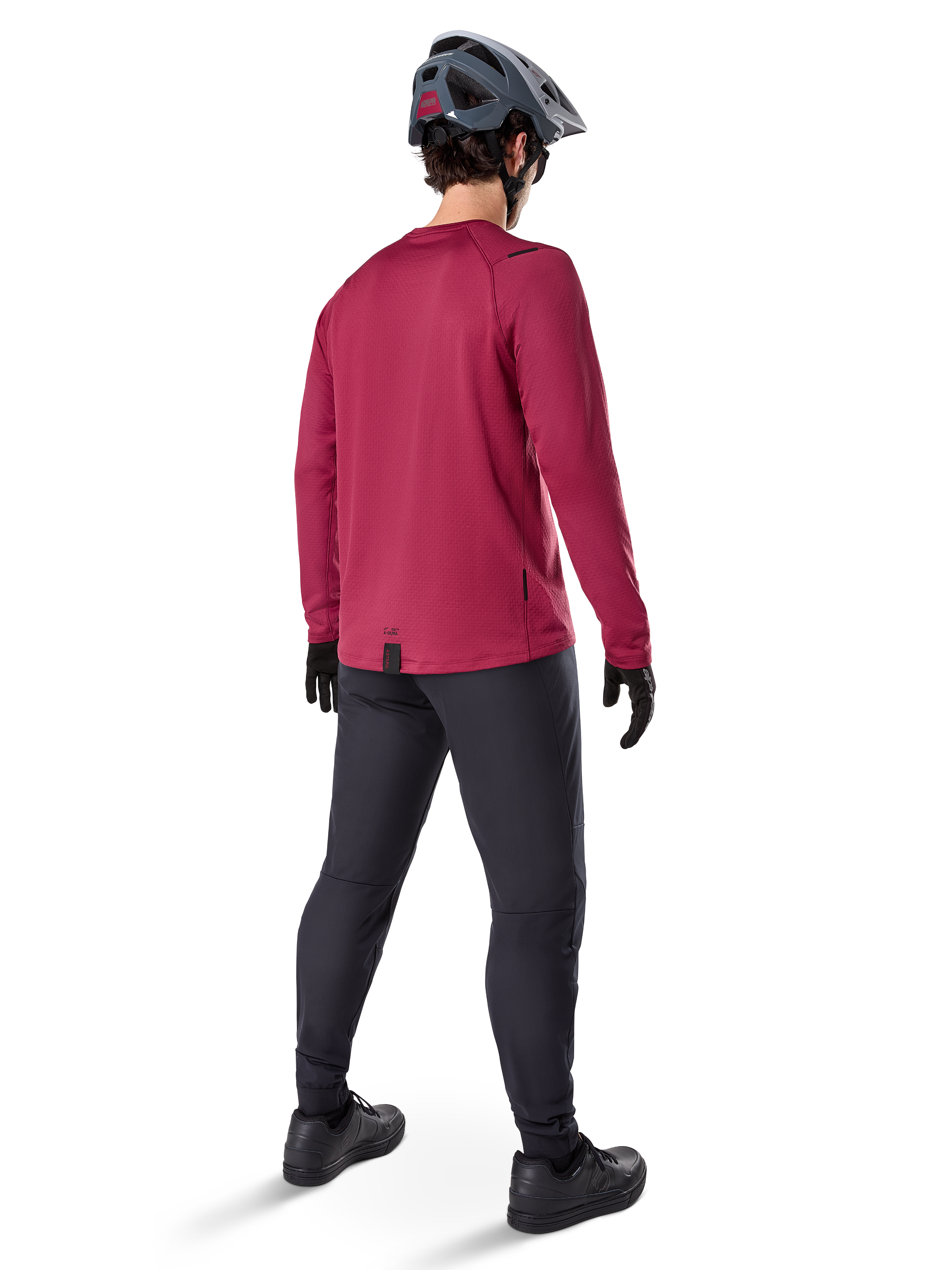 Alpinestars A-Dura Thermal Jersey, bordowa koszulka rowerowa z długim rękawem, widok z tyłu, zestawiona z czarnymi spodniami MTB i szarym kaskiem, przedłużony tył zapewniający osłonę, odzież rowerowa na chłodne dni