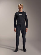 Męski model ubrany w czarną koszulkę z długim rękawem Alpinestars A-Aria Polartec Elite, białe logo Astars na klatce piersiowej i branding na ramionach, czarne techniczne spodnie MTB i buty, profesjonalny zestaw odzieży do kolarstwa górskiego