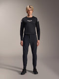 Spodnie Alpinestars A-Aria Elite, spodnie MTB w kolorze Black Titanium, prezentowane przez modela w dopasowanej czarnej koszulce z długim rękawem i sneakersach, wyczynowy krój slim-fit z magnetycznym zapięciem na klamrę, techniczna odzież do kolarstwa górskiego
