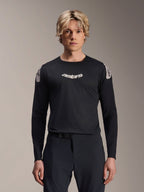 Alpinestars A-Aria Polartec Elite Jersey, koszulka MTB z długim rękawem, czarna, z białym logo „astars” na klatce piersiowej i białą grafiką na ramionach, profesjonalna odzież rowerowa prezentowana przez modela