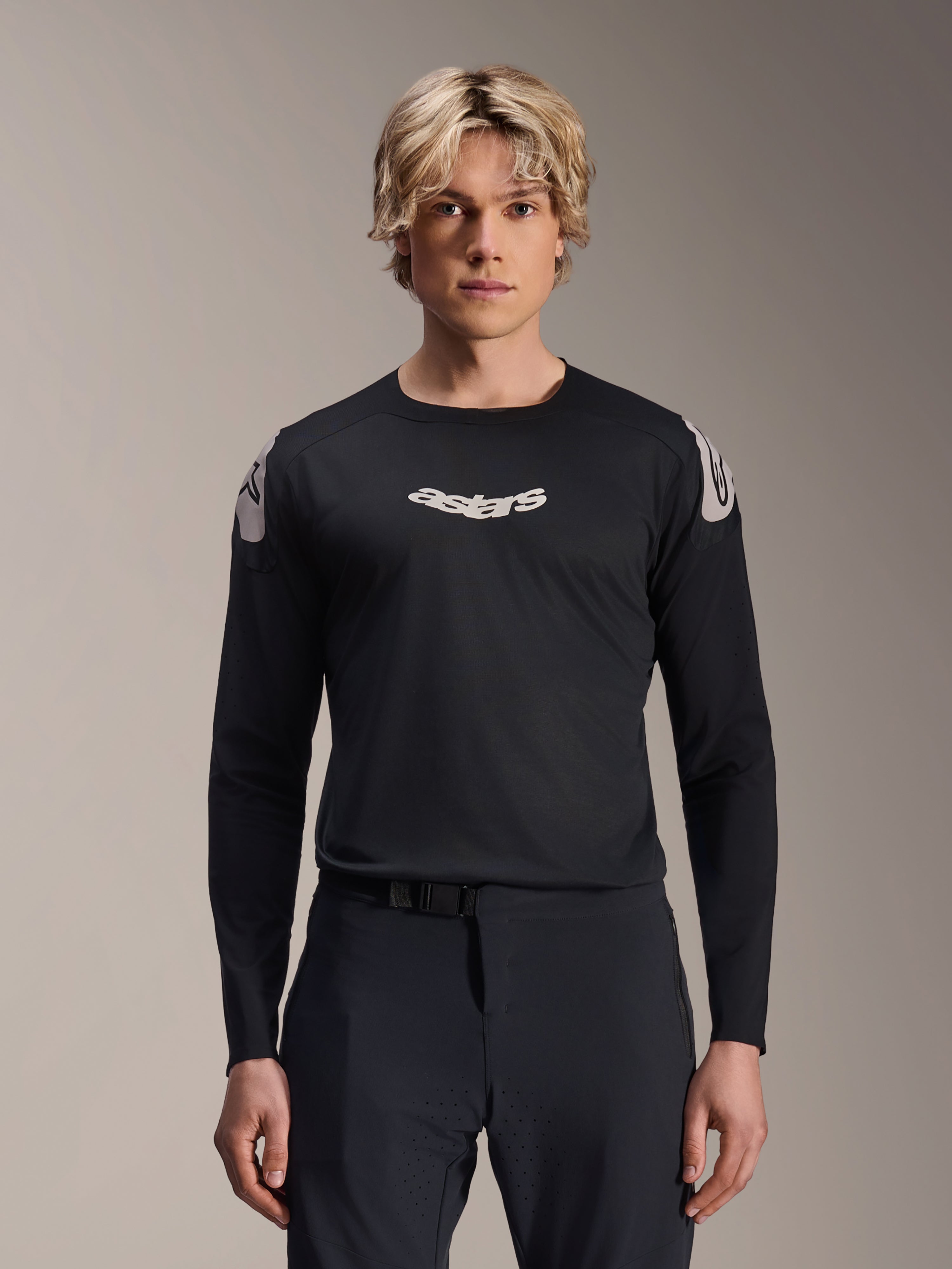 Alpinestars A-Aria Polartec Elite Jersey, koszulka MTB z długim rękawem, czarna, z białym logo „astars” na klatce piersiowej i białą grafiką na ramionach, profesjonalna odzież rowerowa prezentowana przez modela
