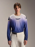 Alpinestars A-Aria Polartec Maker Elite Jersey, koszulka MTB z długim rękawem, kolor Baja Blue z gradientem od bieli do niebieskiego, noszona przez modela w białych spodniach, z ciemnoniebieskim logo na klatce piersiowej i laserowymi perforacjami na rękawach, wyczynowa odzież do kolarstwa górskiego
