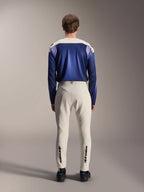Koszulka z długim rękawem Alpinestars A-Aria Polartec Maker Elite, kolor Baja Blue i złamana biel, widok z tyłu na modela w technicznym stroju do kolarstwa górskiego, spodnie w kolorze złamanej bieli z logo Alpinestars na dole nogawek, profesjonalny zestaw rowerowy do jazdy terenowej