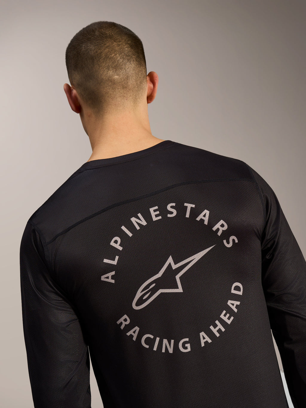 Czarna koszulka A-Dura Air z długim rękawem, detal pleców z okrągłym logo Alpinestars Racing Ahead na siatce.